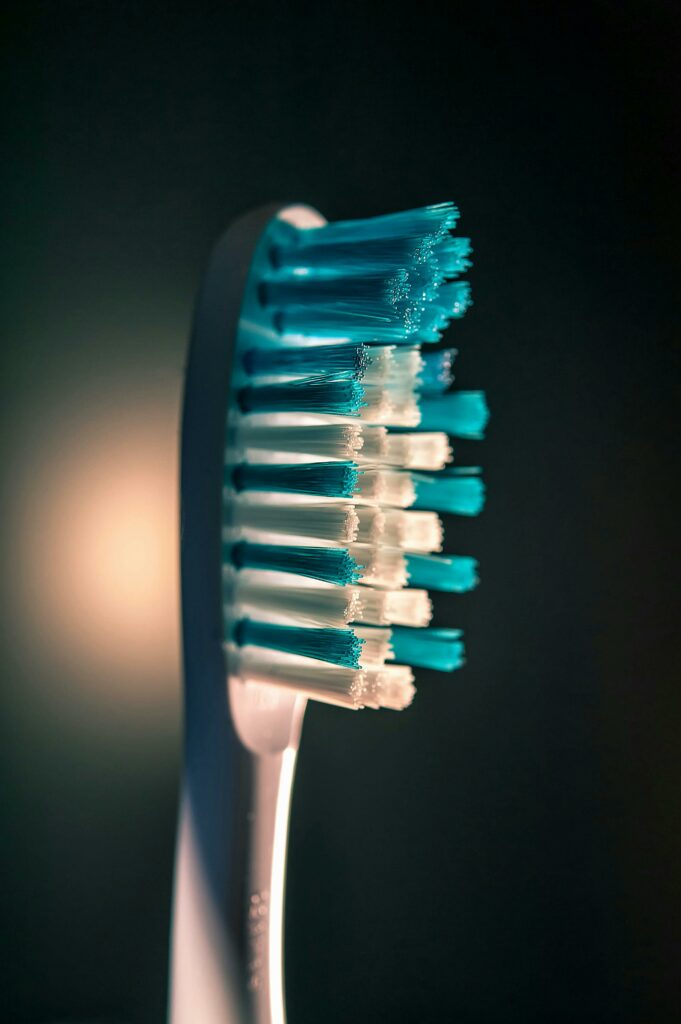 Detailed close-up of a toothbrush with blue and white bristles against a dark background.